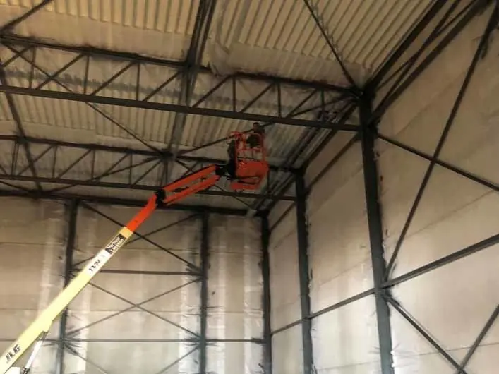 Hoogwerker in een industriële hal tijdens schilderwerken