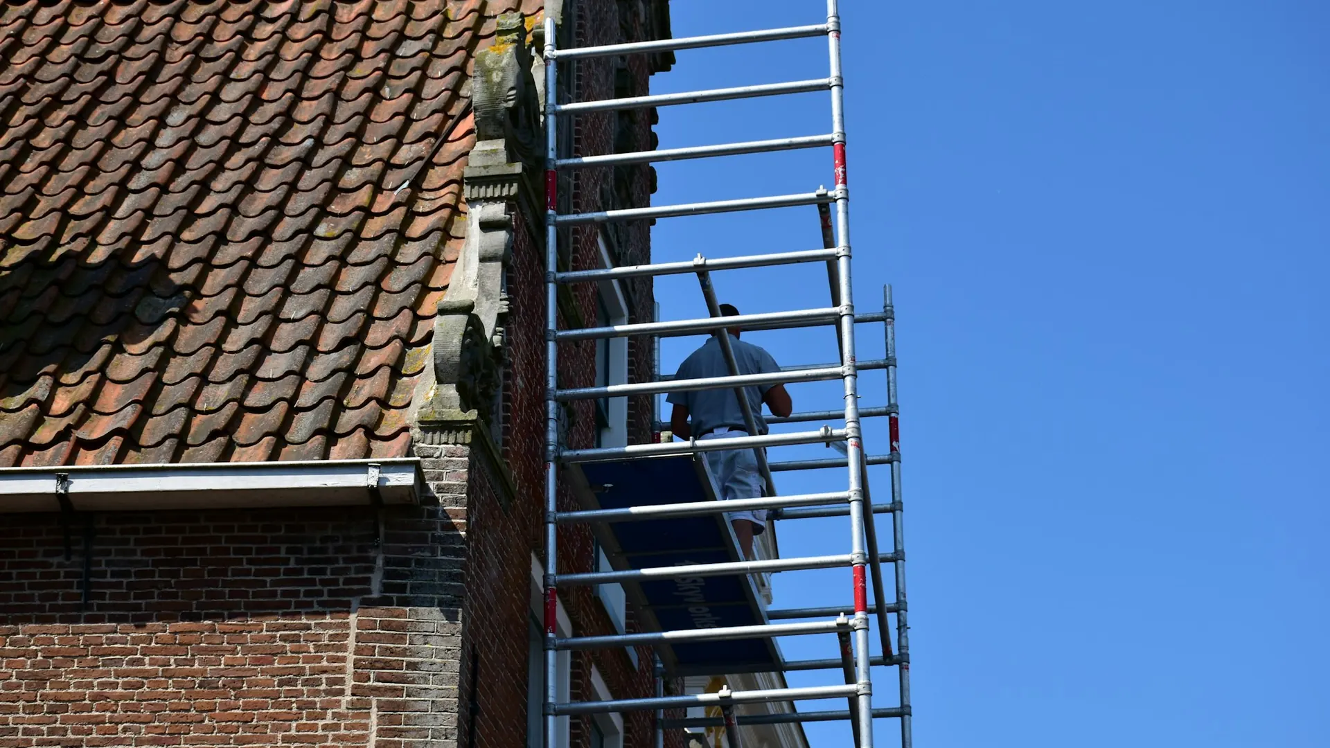 Schilder op een stelling tegen een bakstenen gevel
