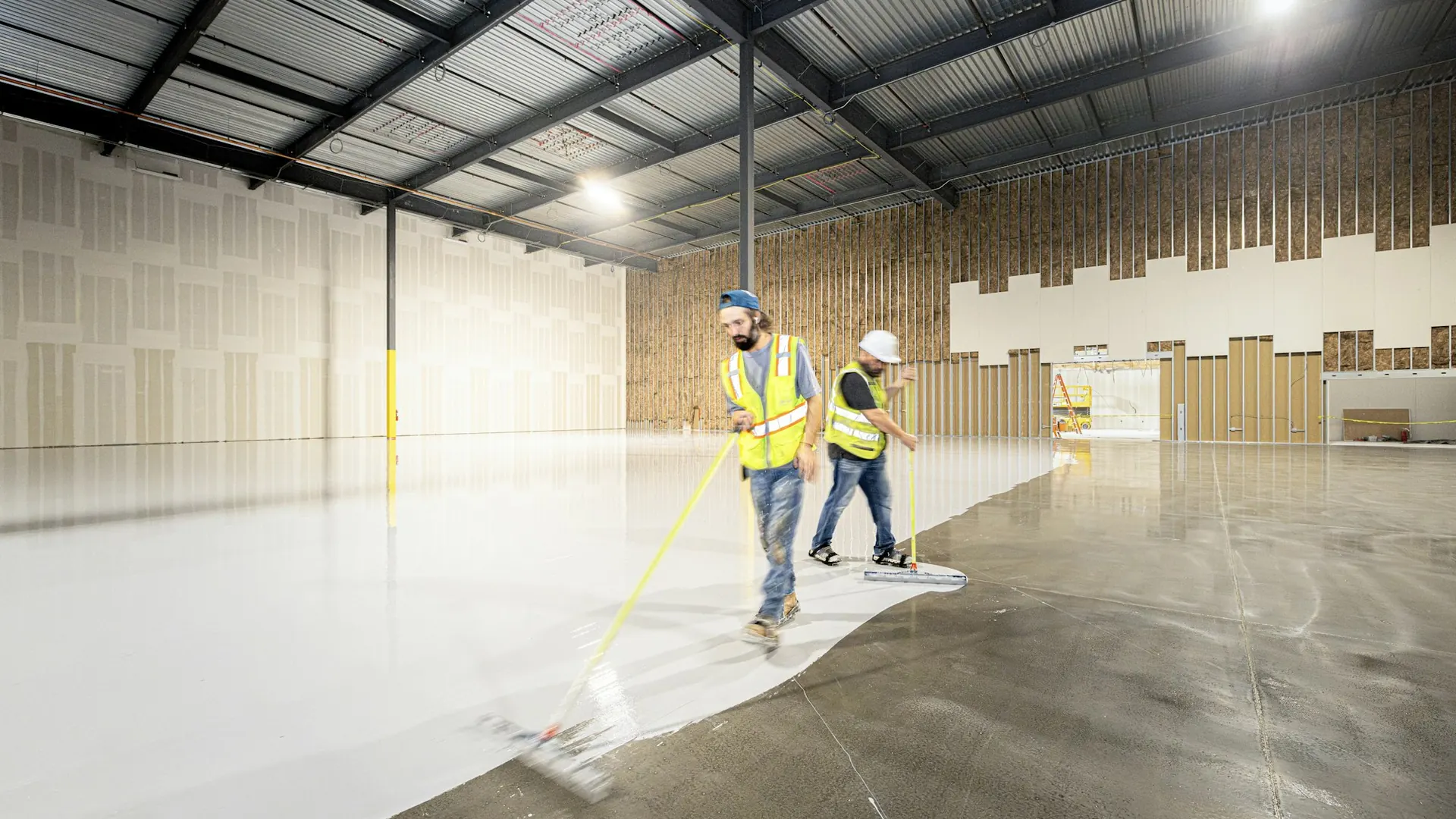 Ploeg brengt een coating aan op de vloer van een industriële hal